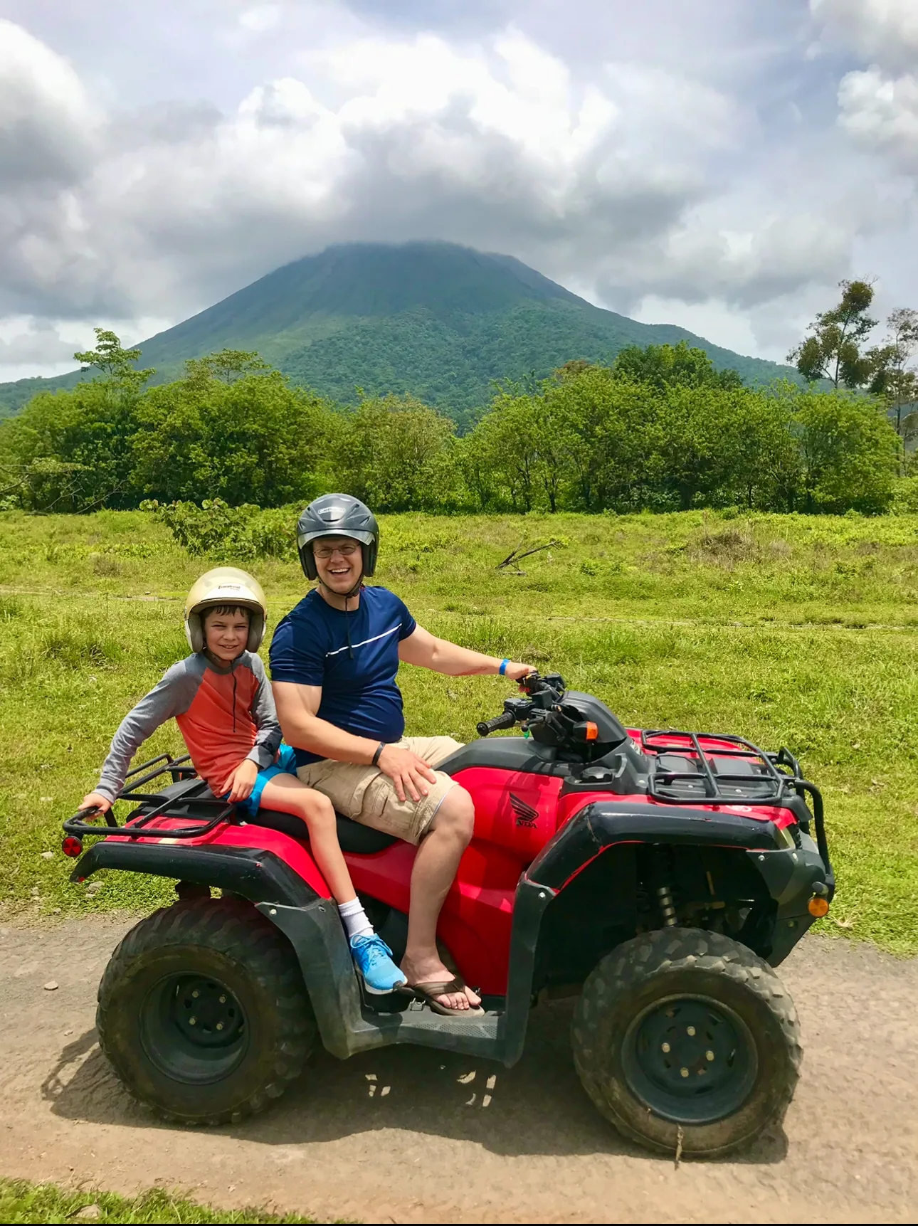 Father and son on a Honda 4x4 quad with Arenal Volcano behind them near La Fortuna, Costa Rica