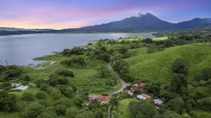 Arenal at dusk over Lake Arenal — the lodge sits on the slope below.